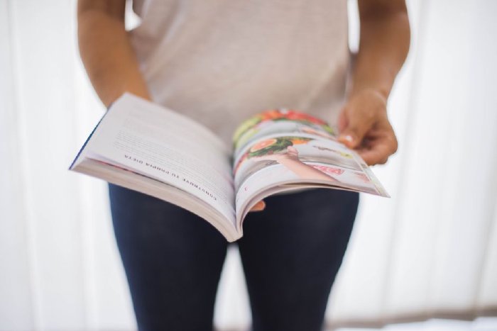 Жена чете книга за хранене в кухнята