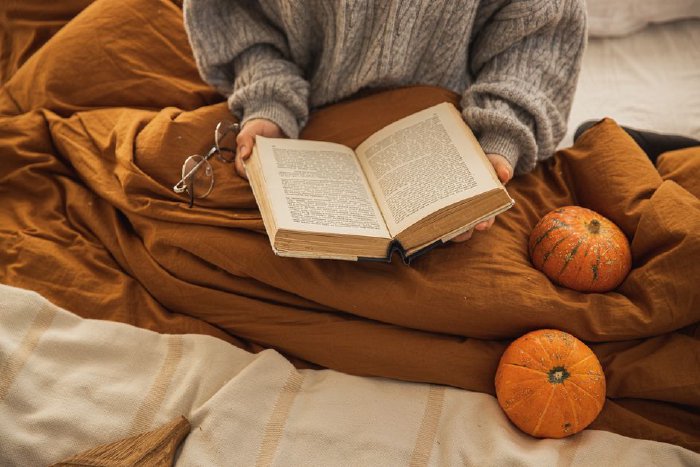 Жена чете книга, завита с одеяло